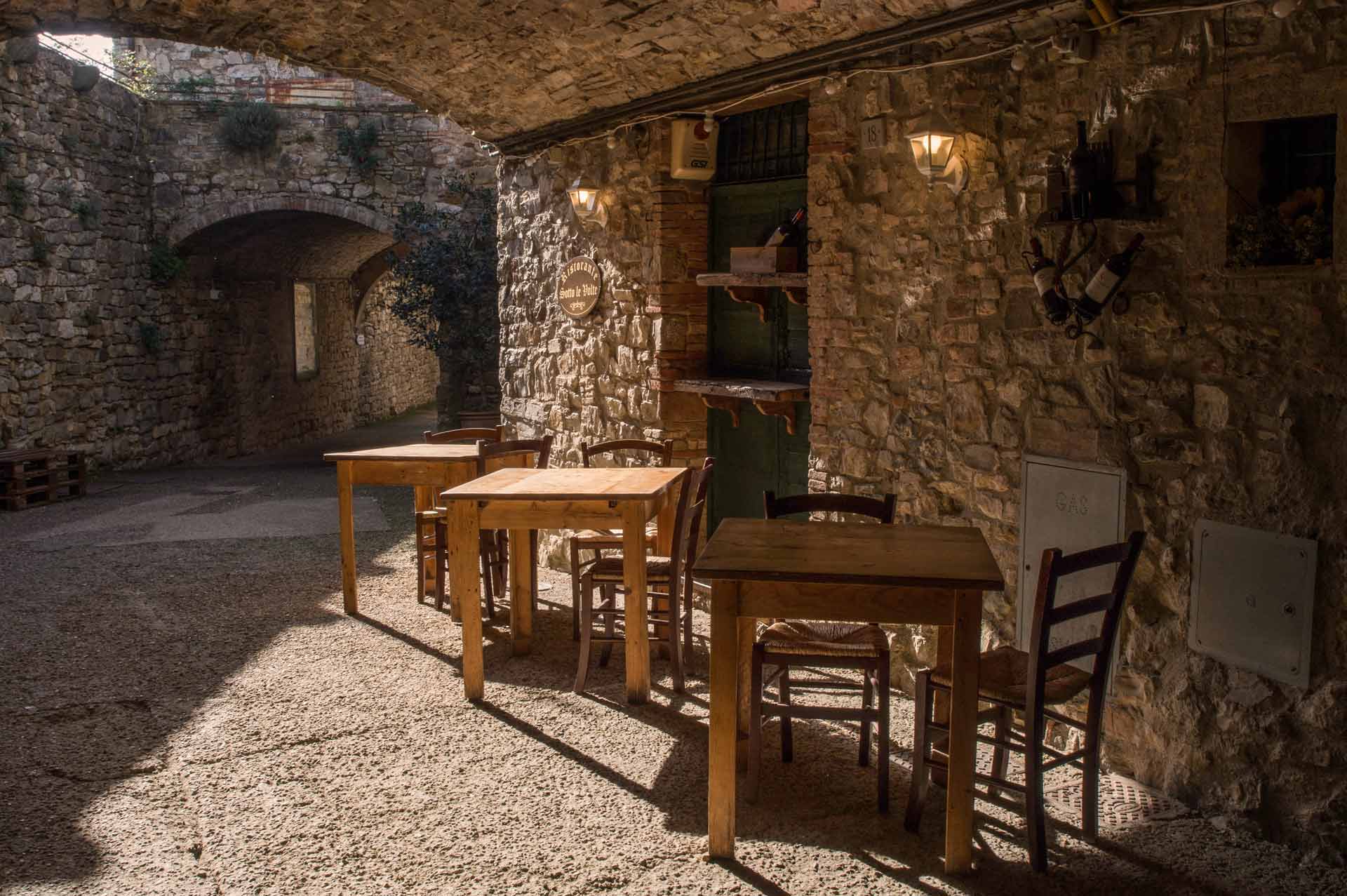 Tavoli di una trattoria tipica in pietra nel centro storico di un borgo del Chianti, Toscana