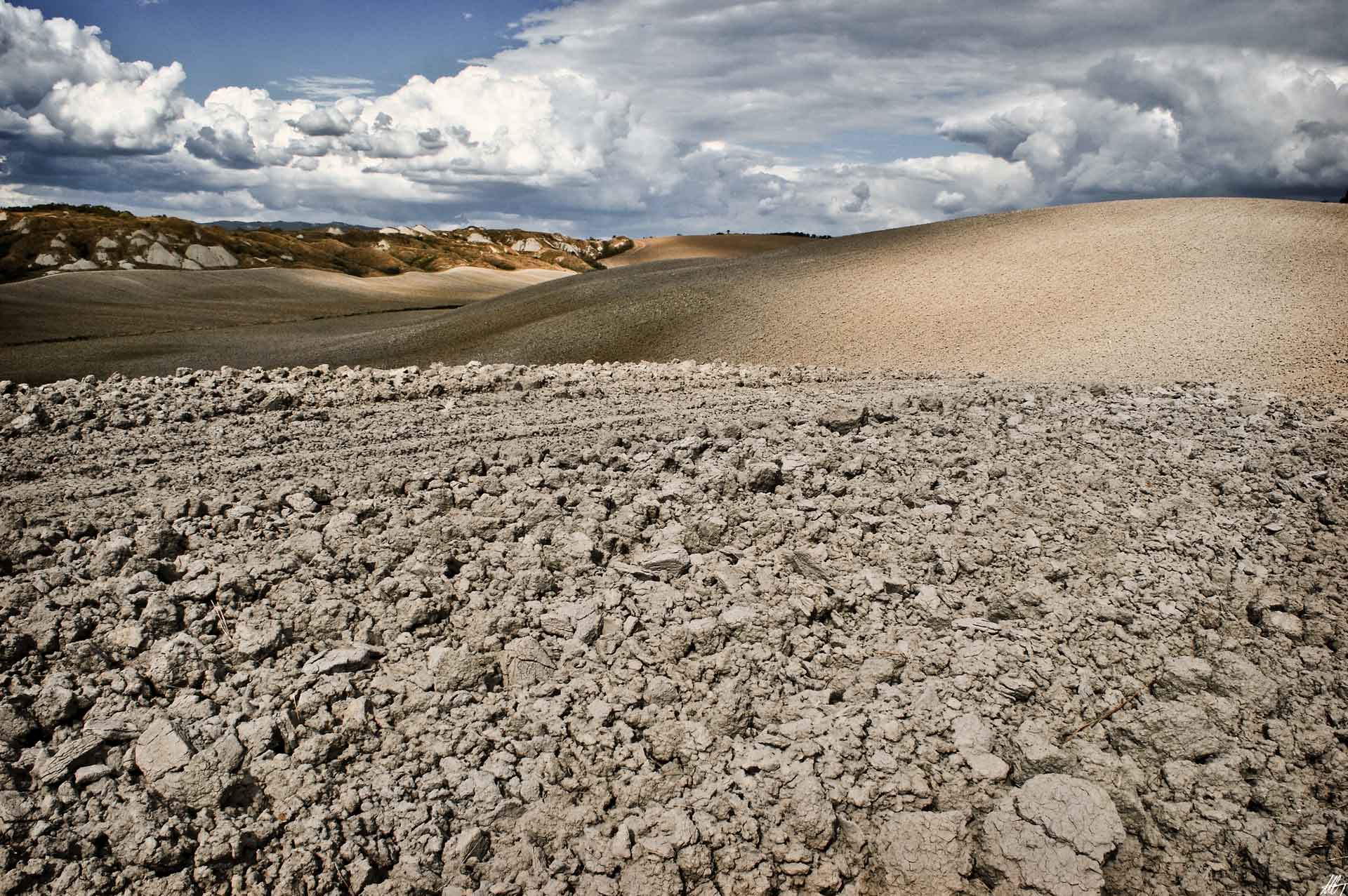 Terreno argilloso e colline tipiche delle Crete Senesi sotto un cielo nuvoloso