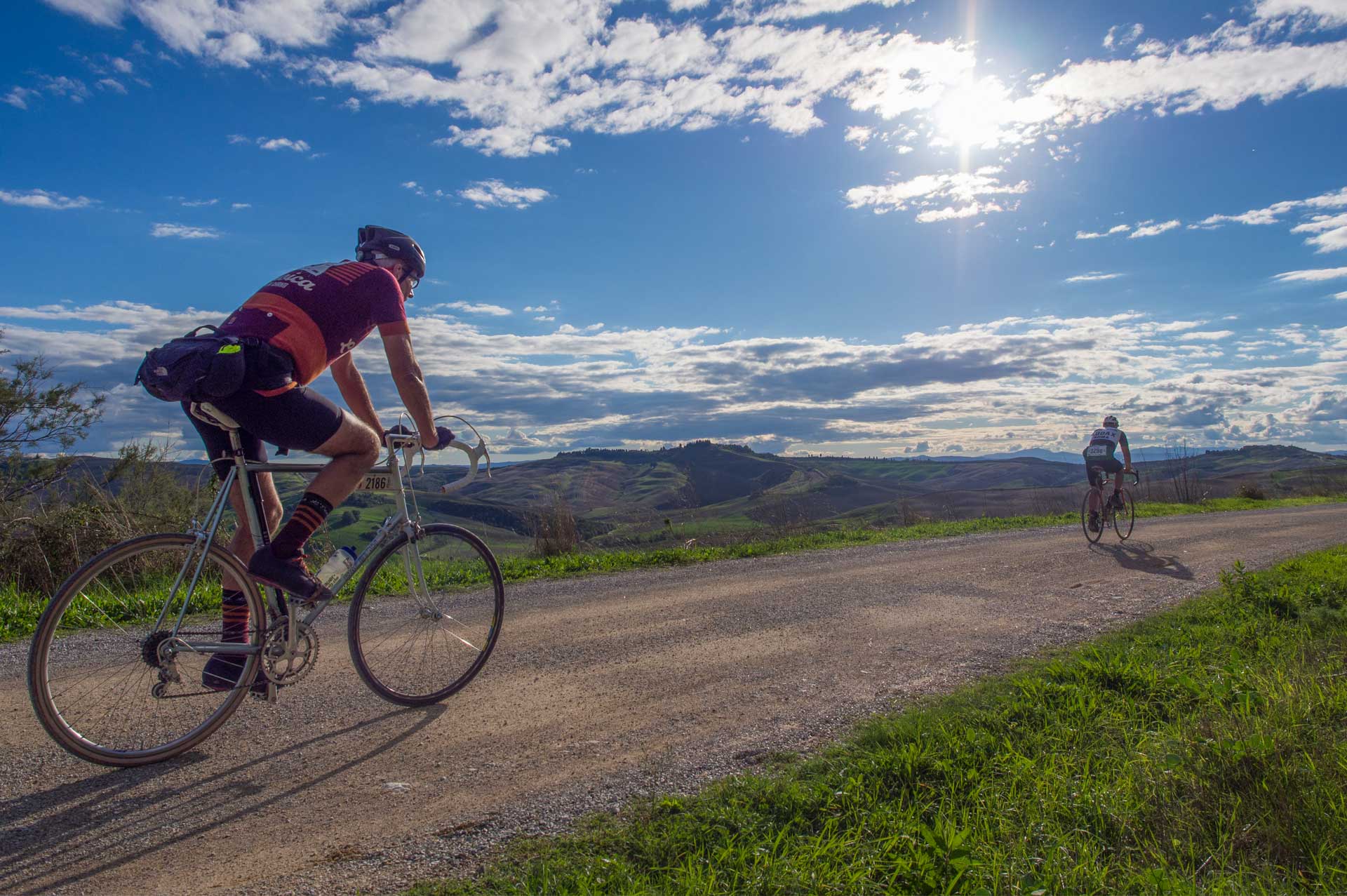 Ciclista illuminato dal sole su strada sterrata al tramonto