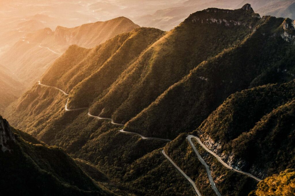Strada montana tortuosa tra pendii al tramonto.